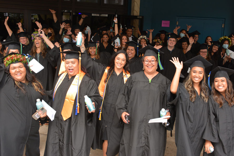 recent graduates cheering and raising their arms in celebration of earning a degree